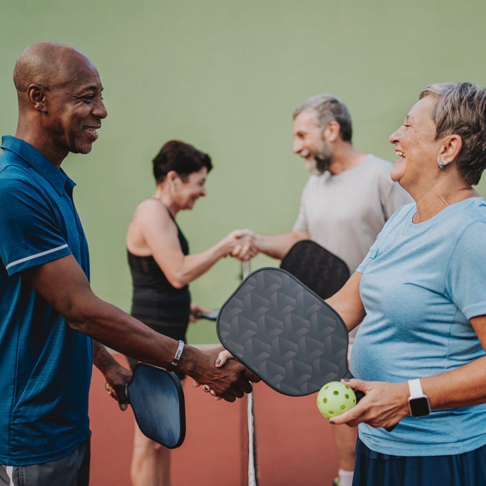 Four adults shaking hands after a pickleball game