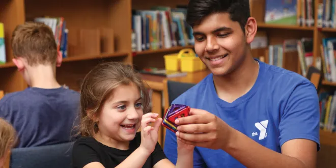 After School counselor helping a child with a learning game.