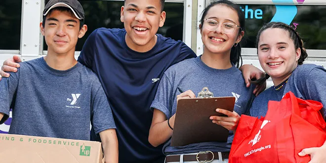 group of four smiling, happy and diverse teenagers volunteering for the YMCA 