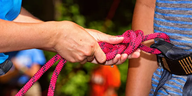 Hands tying knot in preparation for outdoor climbing wall
