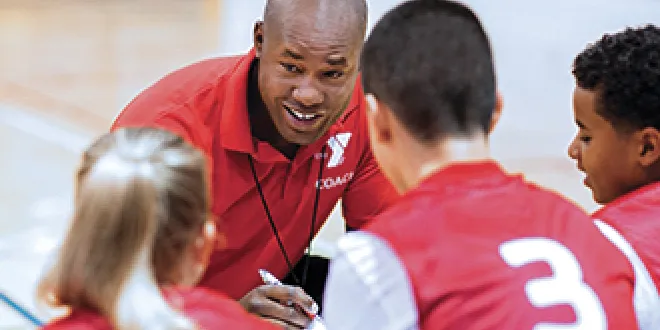 YMCA basketball coach huddles with players