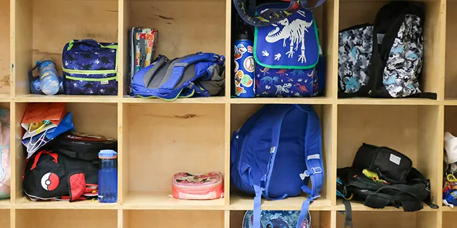 children's backpacks in a wall cubby
