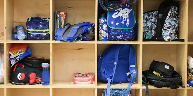 children's backpacks in a wall cubby