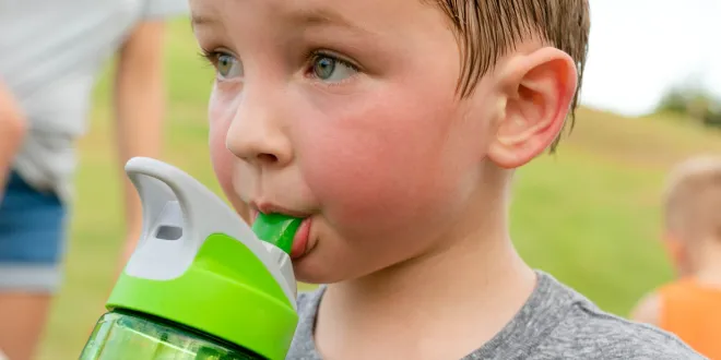 child drinks from water bottle on hot day