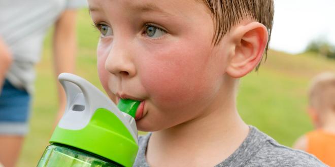 child drinks from water bottle on hot day