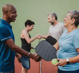 Four adults shaking hands after a pickleball game