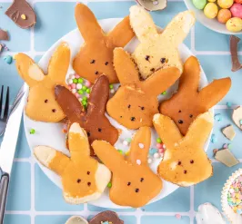 Pancakes in the shape of easter bunnies on a colorful pastel table spread 