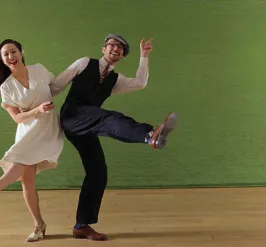 Man and woman smiling while arms are locked doing the swing