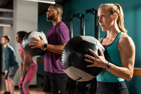 a man and woman using weighted balls to work out at the YMCA