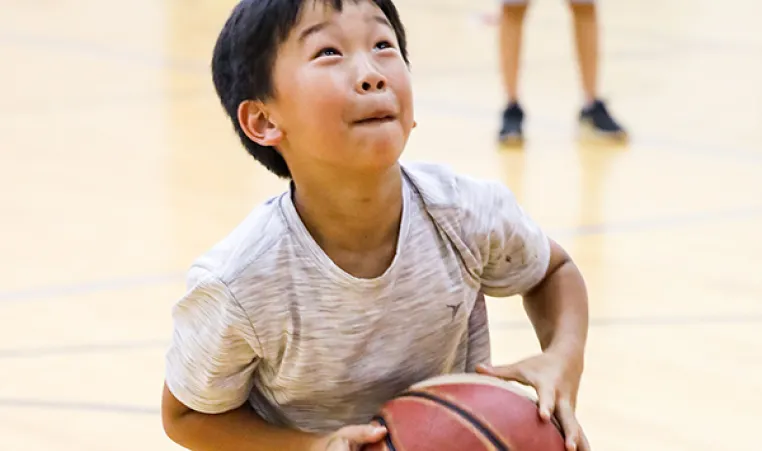 Boy playing basketball at YMCA Holiday camp