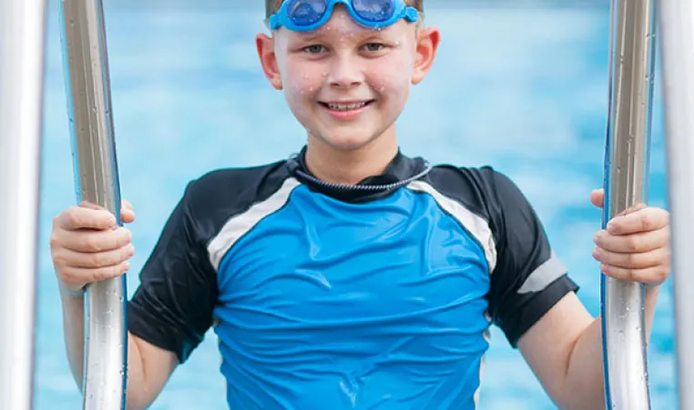Young boy exiting the swimming pool