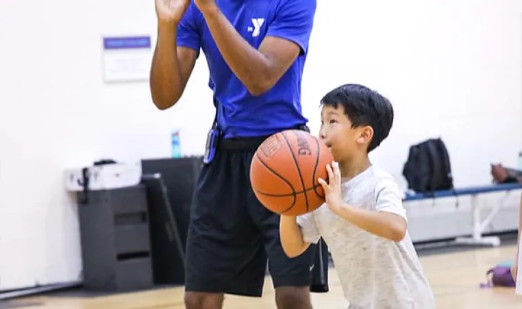 YMCA Counselor and young boy holding a basketball
