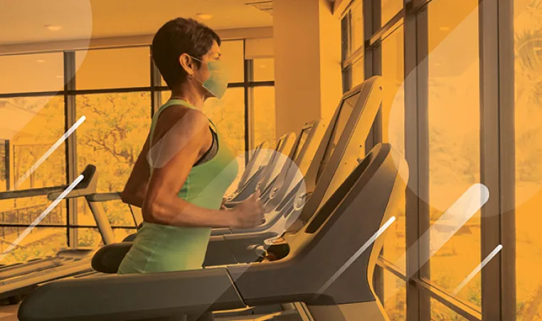 woman running on a treadmill wearing a mask at a YMCA
