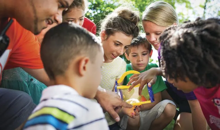 Children surrounding counselor holding butterfly house