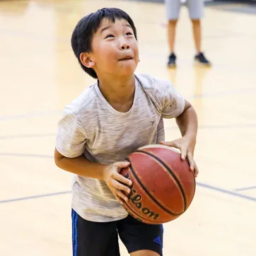 Boy playing basketball at YMCA Holiday camp