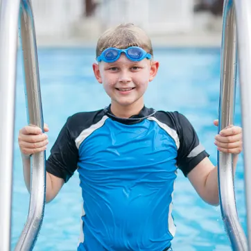 Young boy exiting the swimming pool