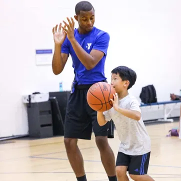 YMCA Counselor and young boy holding a basketball