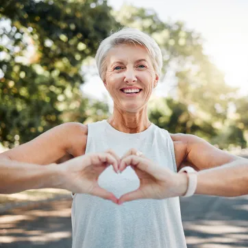 healthy older woman out for a run and making a heart with her hands