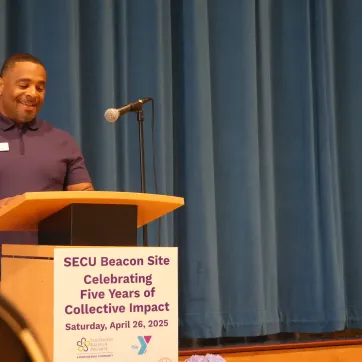 image of man at podium with sign that says SECU Beacon Site Celebrating Five Years of Collective Impact