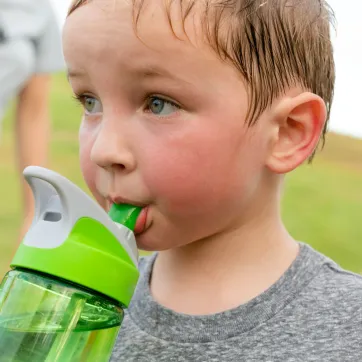 child drinks from water bottle on hot day