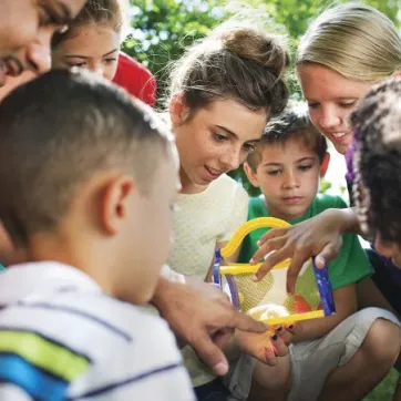 Children surrounding counselor holding butterfly house