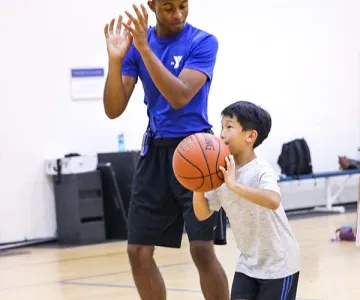 YMCA Counselor and young boy holding a basketball