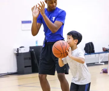 YMCA Counselor and young boy holding a basketball