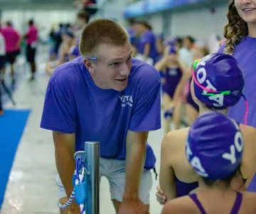 swim team coach giving advice to swimmers