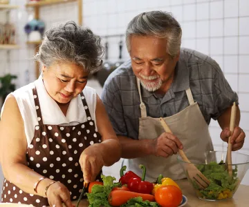 a man and woman chopping vegetables